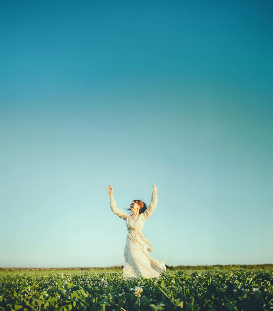 a young girl twirling at sunset in a field